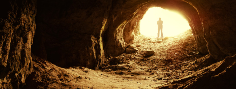 Man,Standing,In,Front,Of,A,Cave,Entrance